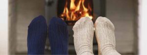 Two people warming their feet in fron of a wood burning stove
